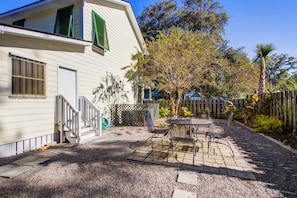 Enjoy a patio with a metal table and chairs, surrounded by lush greenery and a wooden fence.