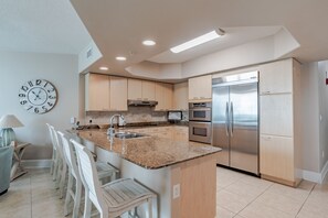 A modern kitchen with granite countertops, stainless steel appliances, and white cabinetry.