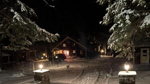 A snow-covered street with a wooden building in the background. - Journeys End Lodging Cabins (Long Lake)