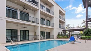 A multi-story building with a swimming pool, balconies, and outdoor seating. - Village Centric Condo w/ Pool Unit 2106 First Floor (St. Simons Island)