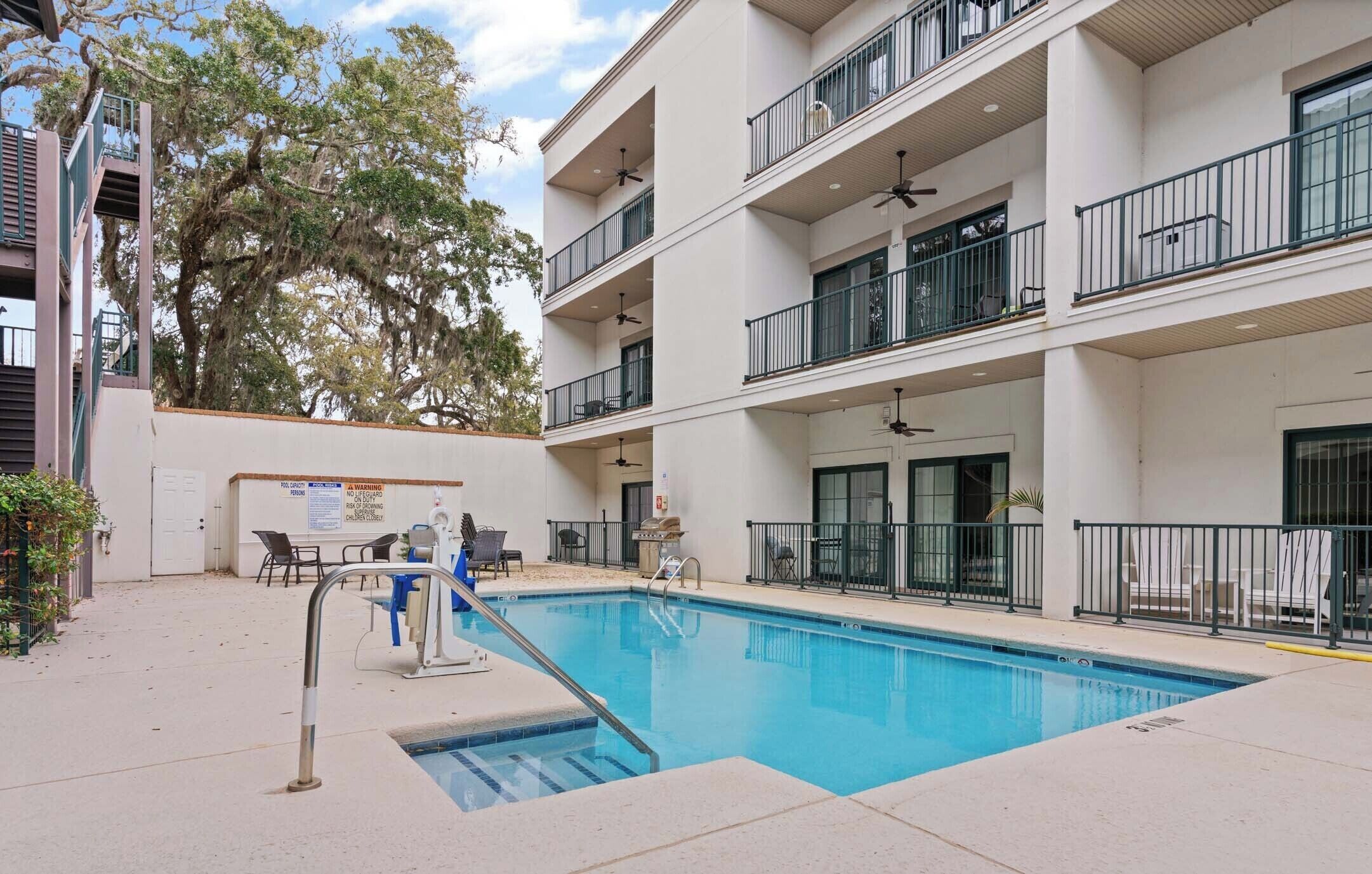 A multi-story building with a swimming pool, outdoor seating, and balconies.