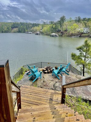 Terraza junto al lago con mobiliario exterior y una chimenea.