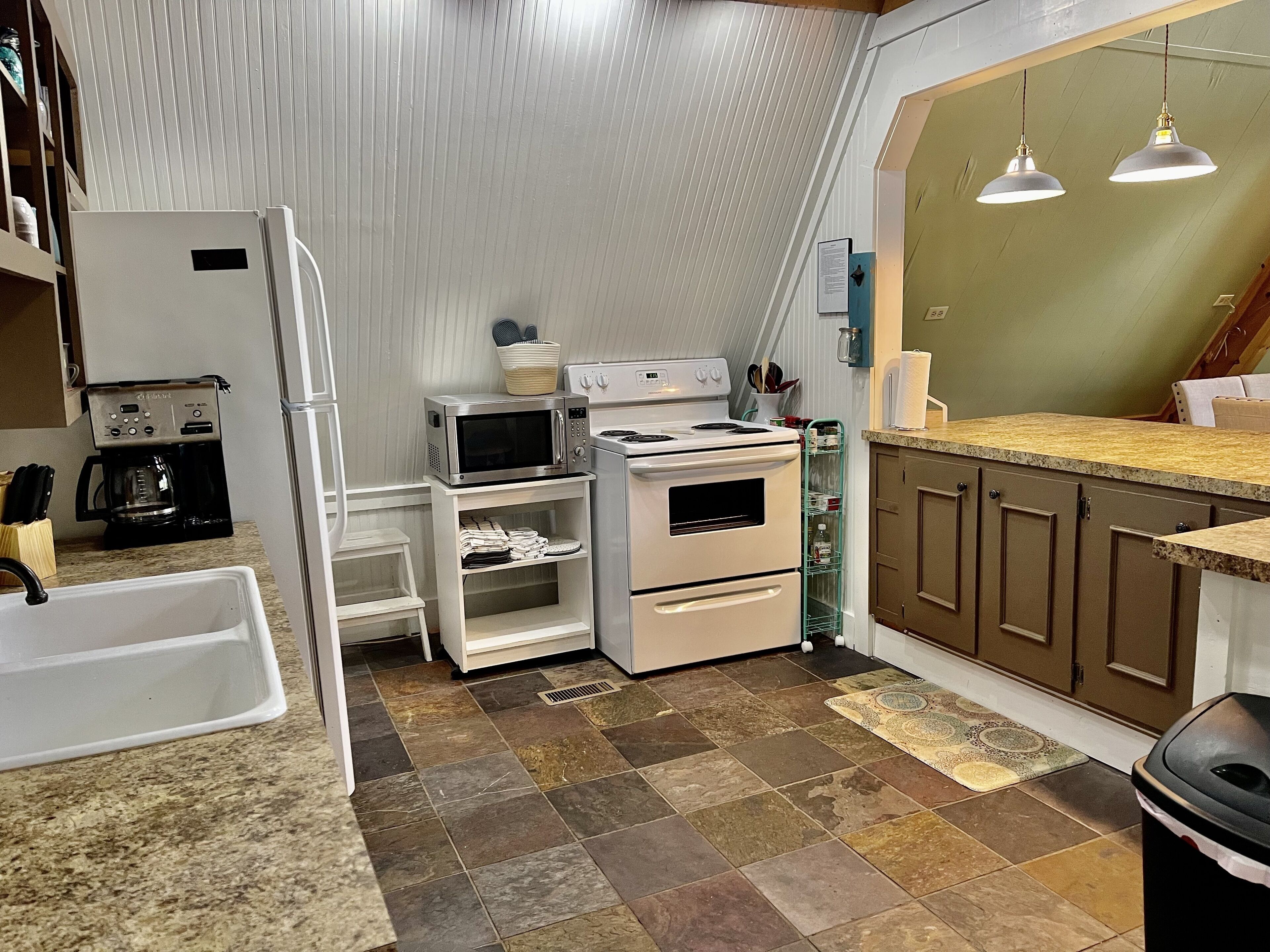 Cozinha compacta com geladeira, micro-ondas, fogão e pia.