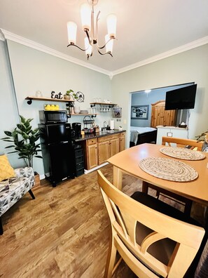 A compact kitchen with a dining area, wooden cabinets, and a black refrigerator.