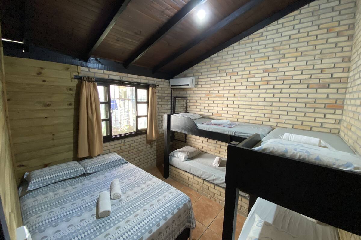 Ein Zimmer mit einem Etagenbett, einem Einzelbett und einem Fenster mit Vorhängen.