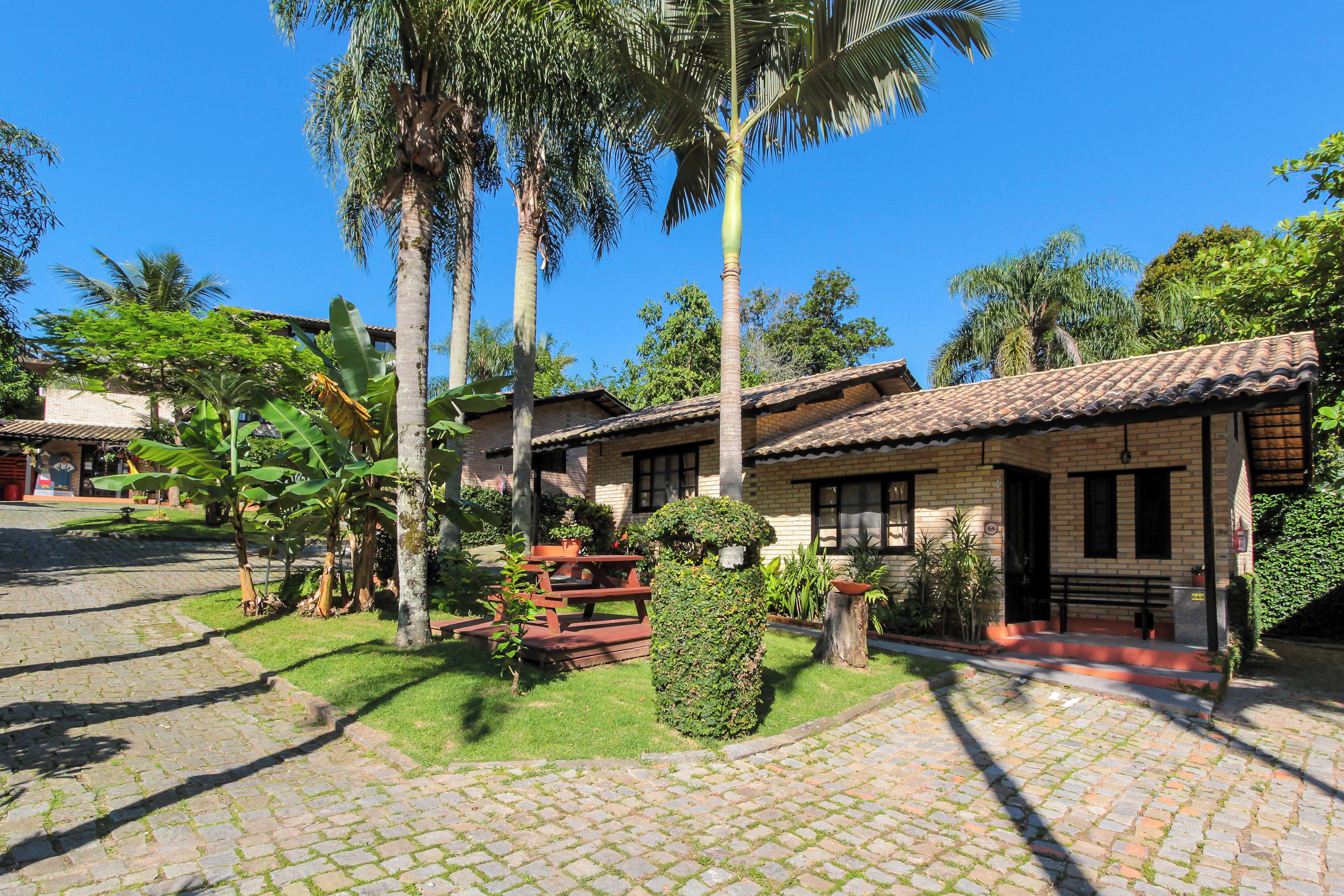 A courtyard with cobblestone paths, a picnic table, and a well-maintained garden with palm trees and shrubs.