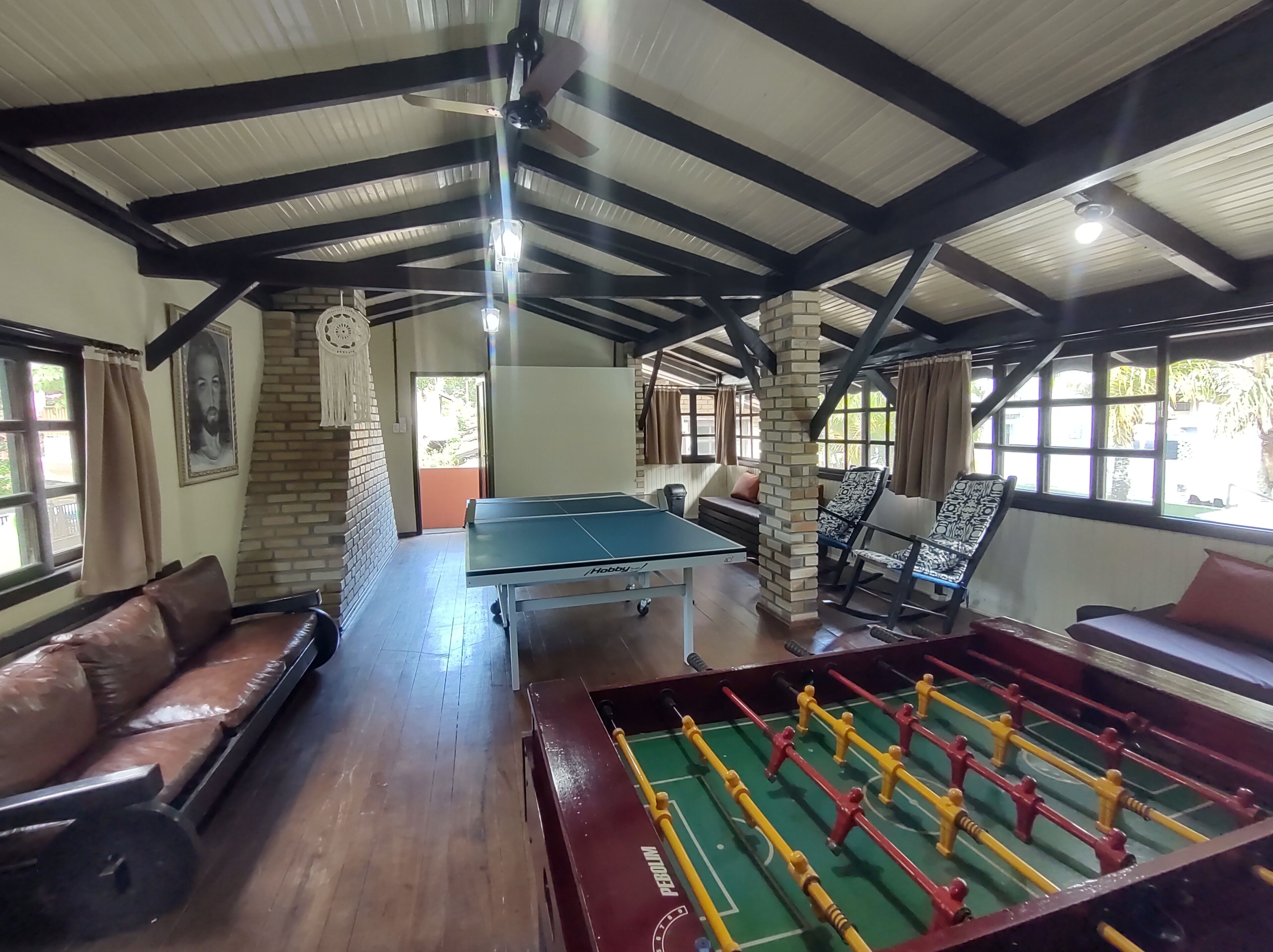 A room with a foosball table, a pool table, and a sofa.