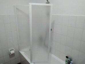 Een badkamer met douchecabine, toilet en wastafel met toiletartikelen.