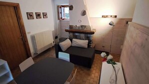 Un espacio habitable compacto con sofá, mesa, radiador y chimenea de piedra.