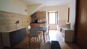 Una cocina compacta con comedor, un refrigerador pequeño y un televisor.