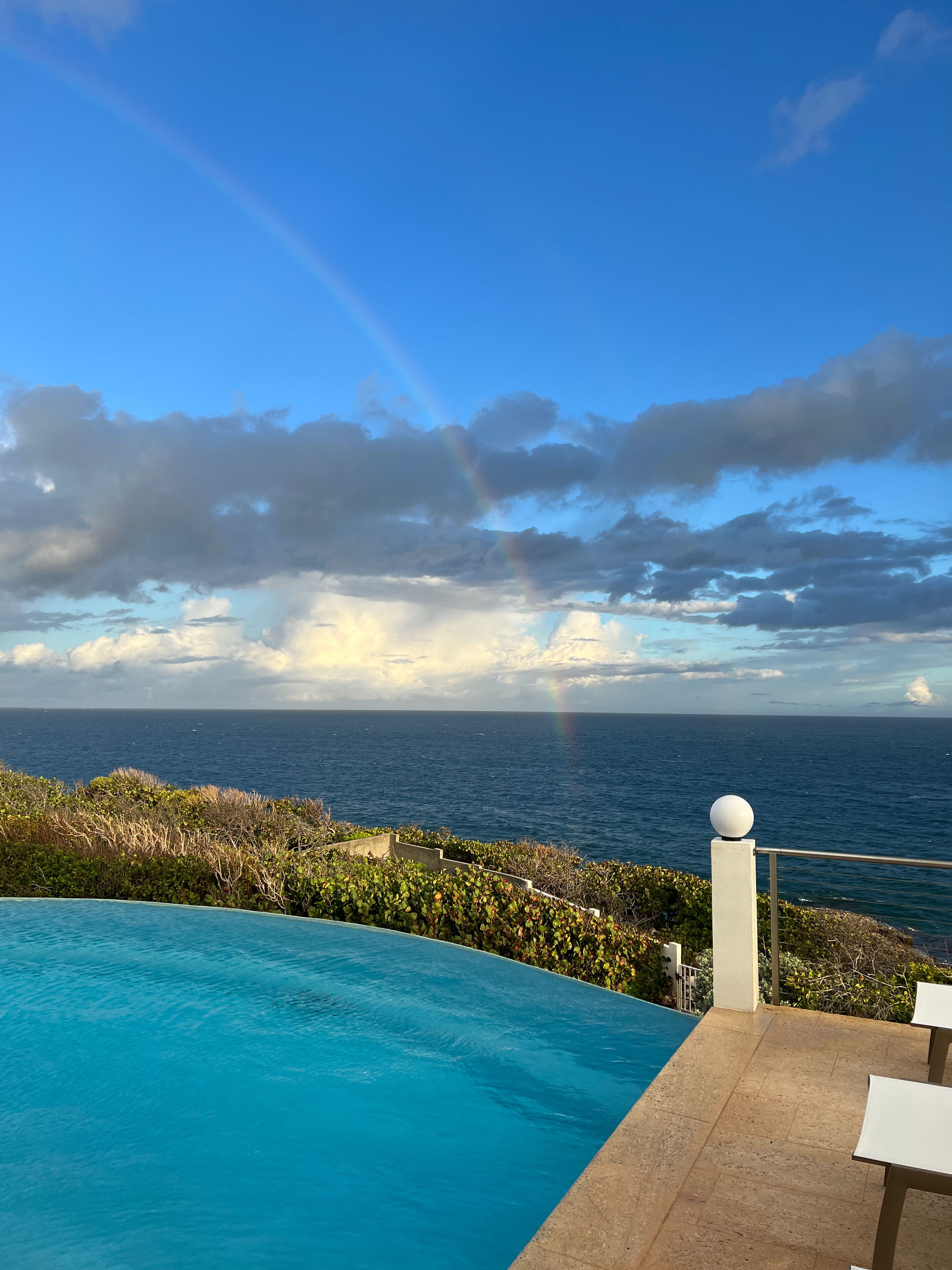 Una piscina con vista al océano y un arcoíris.