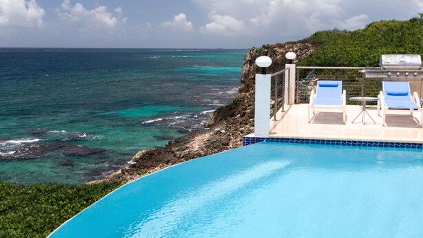 A clear blue pool with lounge chairs and a view of the ocean. - Luxury 4 Bedroom, 7 Bathroom Villa on Shoal Bay, Anguilla (Shoal Bay)