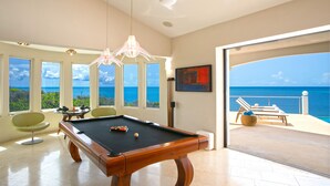 A pool table in a room with large windows overlooking the ocean, a dining area, and a balcony with a view of the sea. - Luxury 4 Bedroom, 7 Bathroom Villa on Shoal Bay, Anguilla (Shoal Bay)