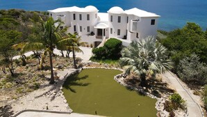 A white building with multiple floors, a swimming pool, and a view of the sea. - Luxury 4 Bedroom, 7 Bathroom Villa on Shoal Bay, Anguilla (Shoal Bay)