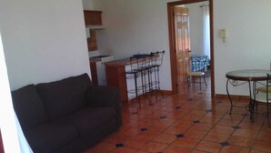 A living room with a sofa, a dining table with chairs, and a kitchen area with a stove and bar stools. - ZONA DORADA BALBOA APARTAMENT 1 (Mazatlán)