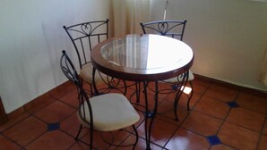 A round glass table with four chairs, each with a cushioned seat, in a room with tiled flooring. - ZONA DORADA BALBOA APARTAMENT 1 (Mazatlán)