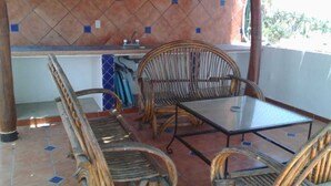 A patio area with wicker furniture, a glass table, and a tiled floor. - ZONA DORADA BALBOA APARTAMENT 1 (Mazatlán)