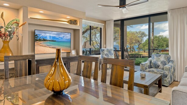 A modern living room with a large TV, wooden furniture, and a view of the outdoors.