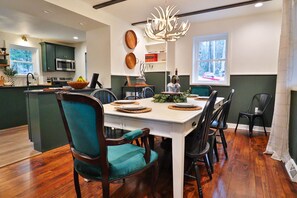 A dining area with a white table, teal chairs, and a chandelier.