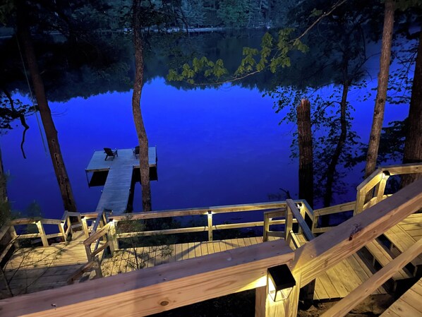 Un muelle de madera que se adentra en un lago tranquilo rodeado de árboles.