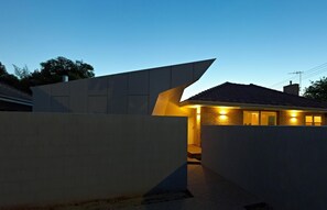 A modern house with a unique angular design, a visible entrance, and a brick exterior.