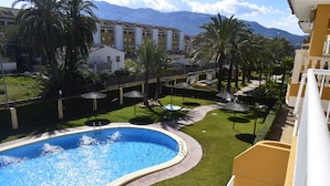 Una piscina de borde curvo, rodeada por un césped cuidado y palmeras.