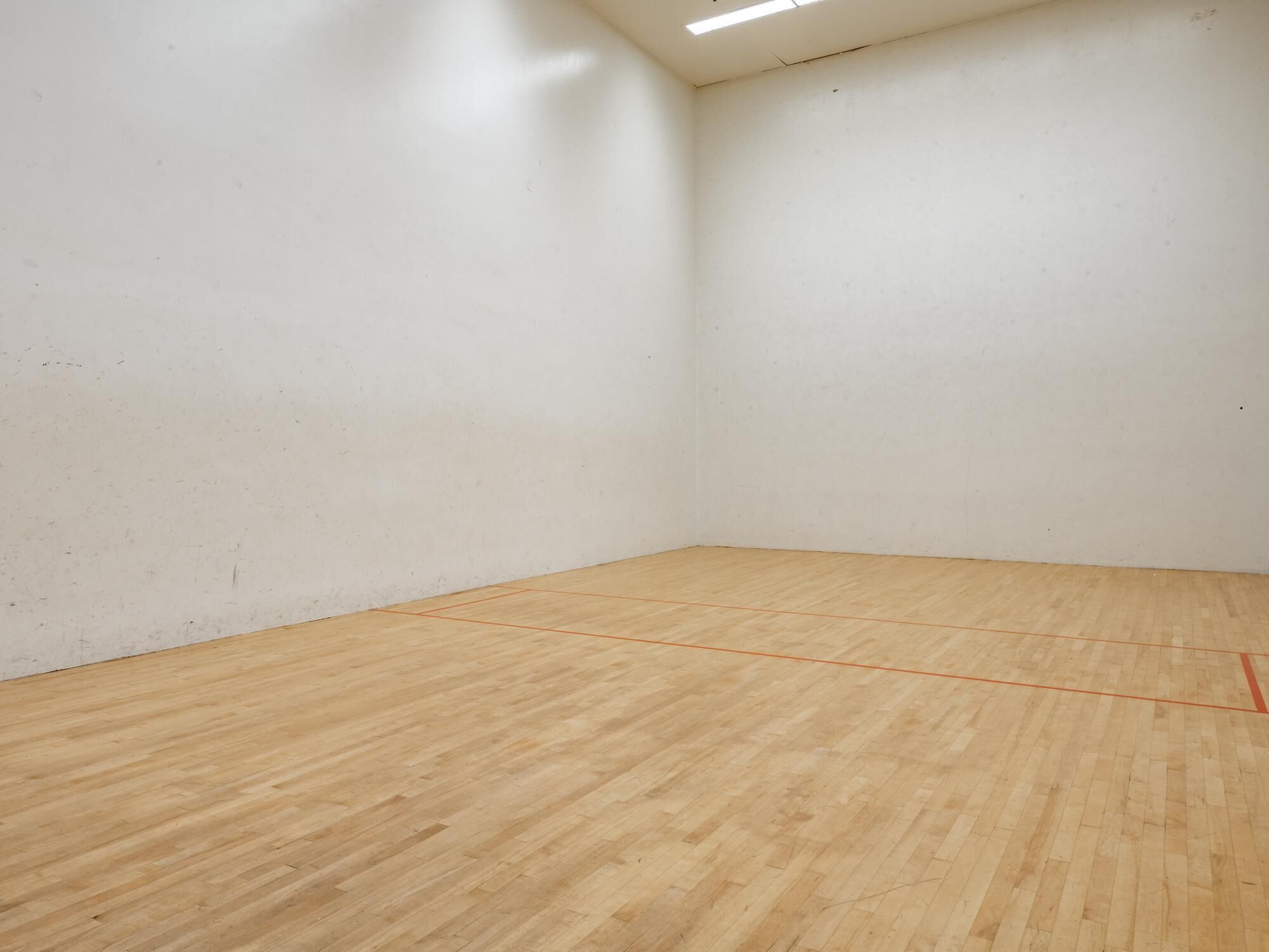 Une pièce avec un plancher en bois et des murs blancs.
