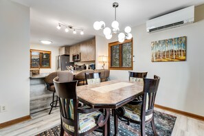 A modern kitchen with built-in appliances, a dining area with a large table and chairs, and a painting on the wall.
