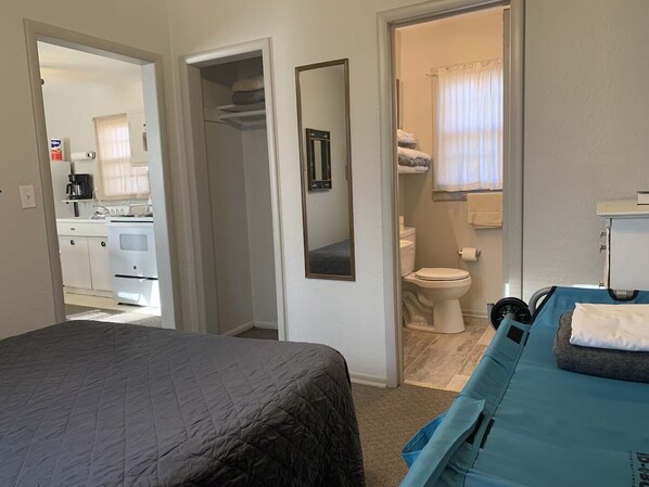 A hotel room with a bed, a bathroom, and a kitchenette.