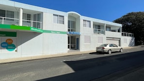 A building with a green sign for Terry White Chemmart, a blue sign for The Avenues, and a car parked in front. - Avenues Unit 1 (South West Rocks)