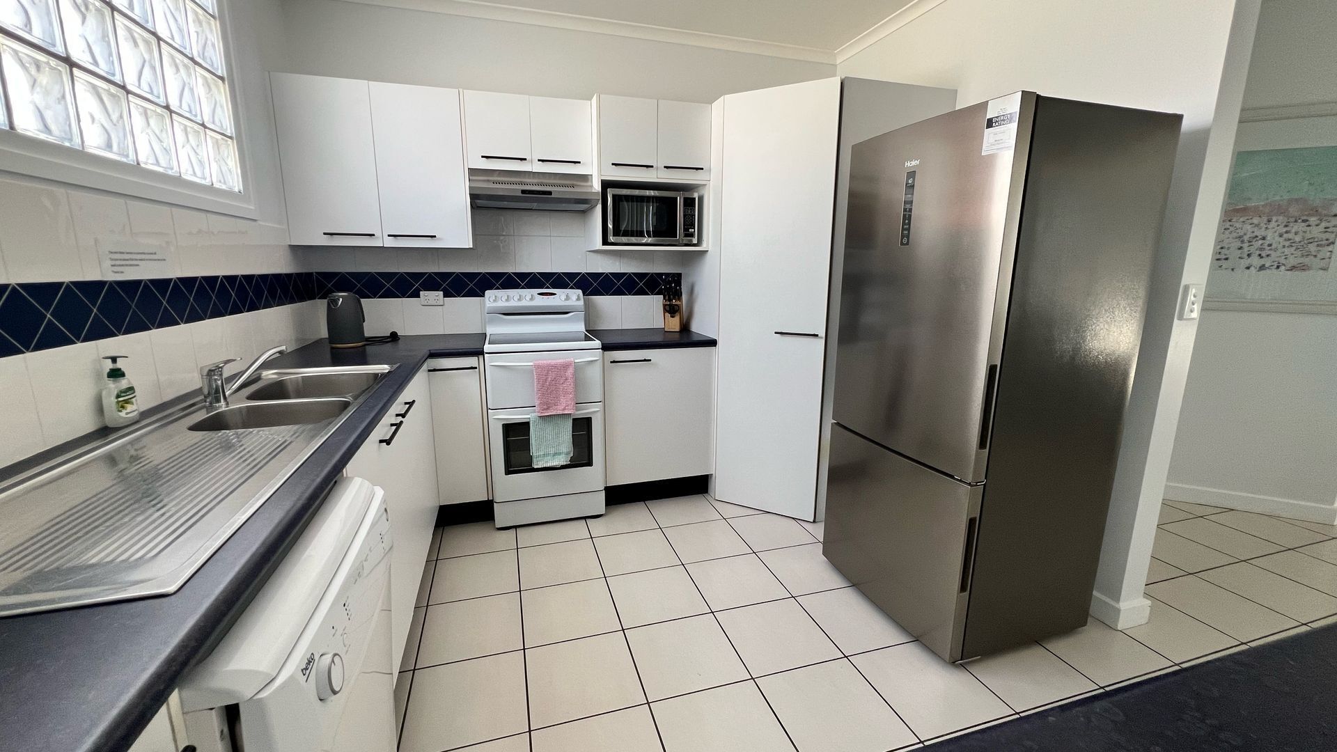 A kitchen with white cabinets, a stainless steel refrigerator, a microwave, and a stove.