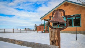 Una cabaña de madera con un silbato en un poste, rodeada de nieve.
