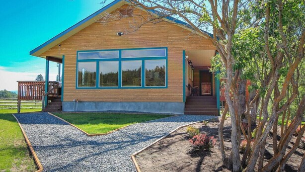 Una casa moderna de madera con ventanas amplias y un porche cubierto.