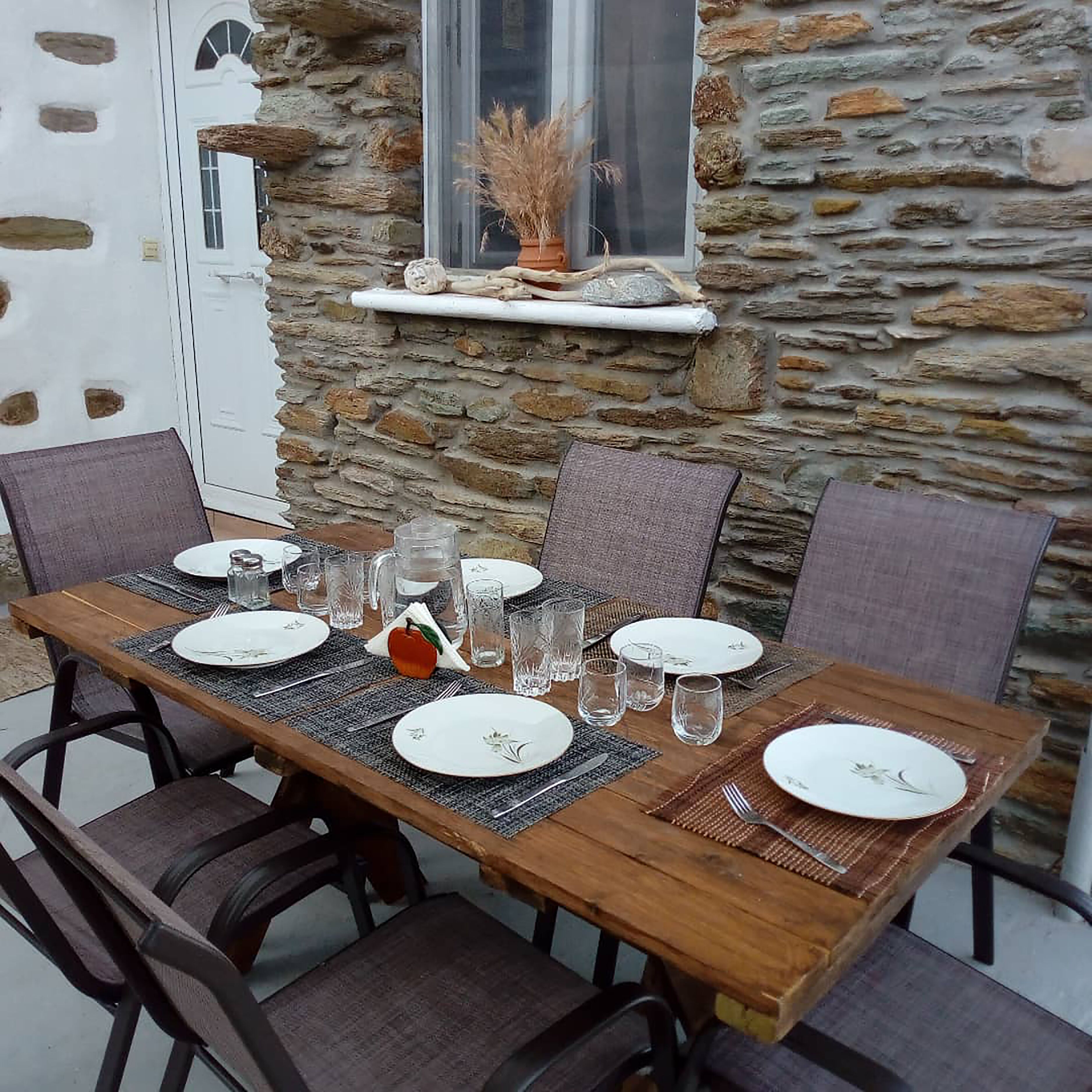A stone wall with a window and a small shelf with dried plants.