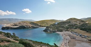 A coastal area with a beach, rocky terrain, and a small building.