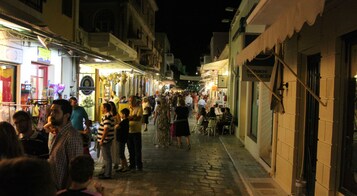 Una calle concurrida por la noche, con gente caminando y parada.