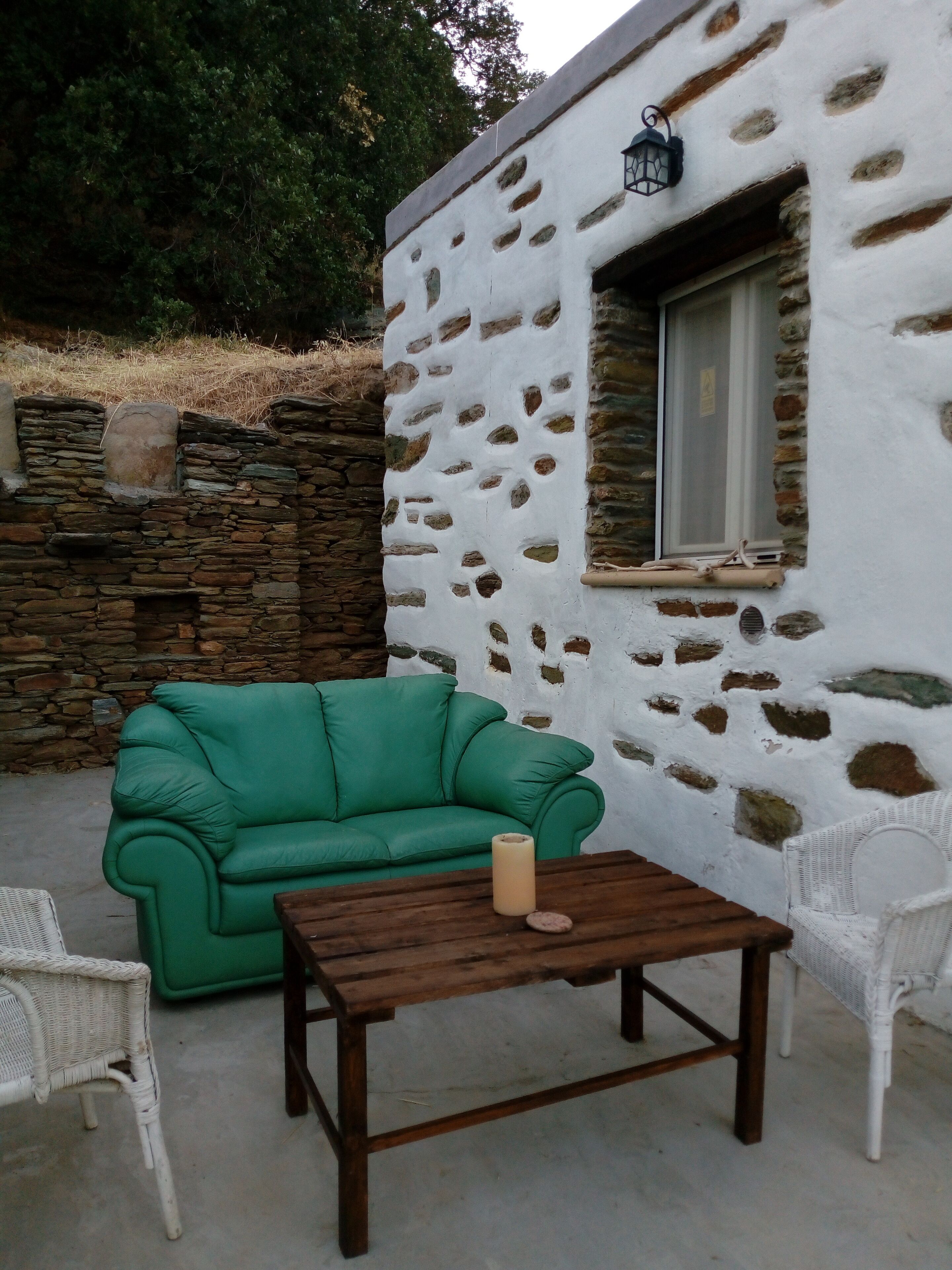 A stone building with a window and a green sofa outside.