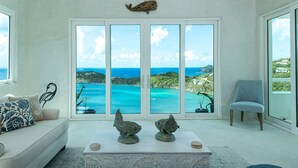 Ein modernes Wohnzimmer mit einem großen Schiebeglasfenster, das einen herrlichen Blick auf den Ozean bietet.