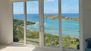 Ein Zimmer mit großen Schiebeglasfenstern, die einen schönen Blick auf eine Küstenlandschaft bieten.