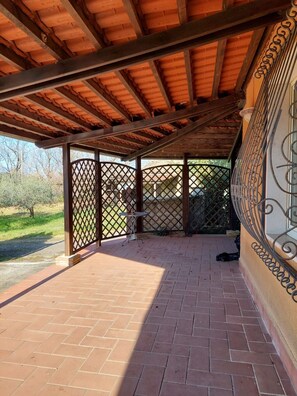 Un espacio de patio techado con piso de ladrillo, paneles de celosía metálica y techo de madera.