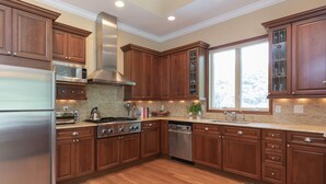 A modern kitchen with wooden cabinets, stainless steel appliances, and a large window providing natural light. - Bridgehampton gem in private community- 1 mile from the village (Bridgehampton)