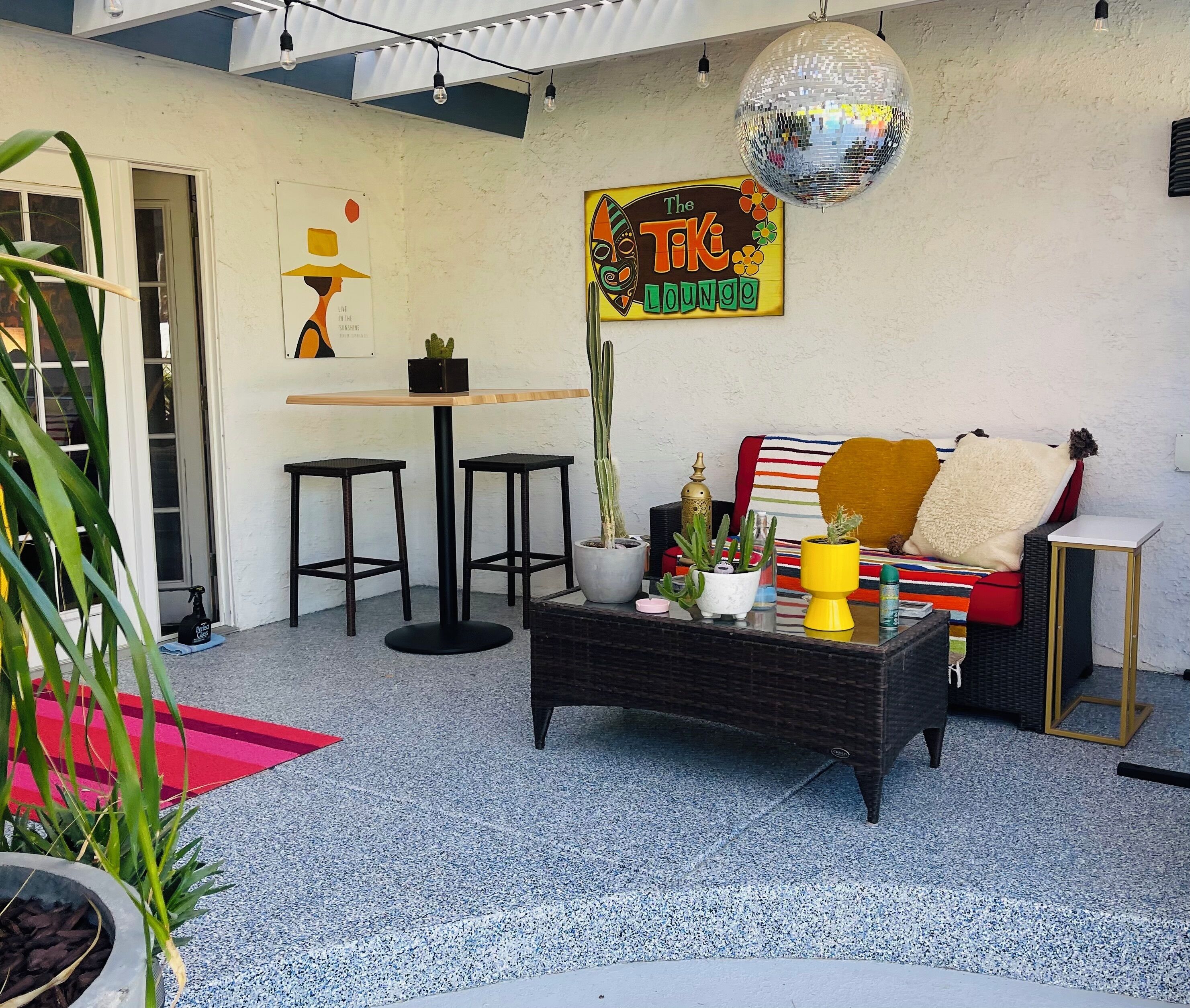 Un espace patio accueillant avec une table, des chaises, un canapé et une enseigne indiquant « The Tiki Lounge ».