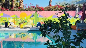 A pool area with lounge chairs, a colorful mural, and potted plants. - An Entire Private Studio Suite to Yourself! (Palm Desert)