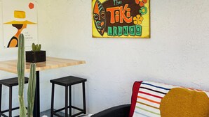 A cozy lounge area with a wooden table, black stools, a cactus plant, a decorative sign, and a colorful striped pillow. - An Entire Private Studio Suite to Yourself! (Palm Desert)