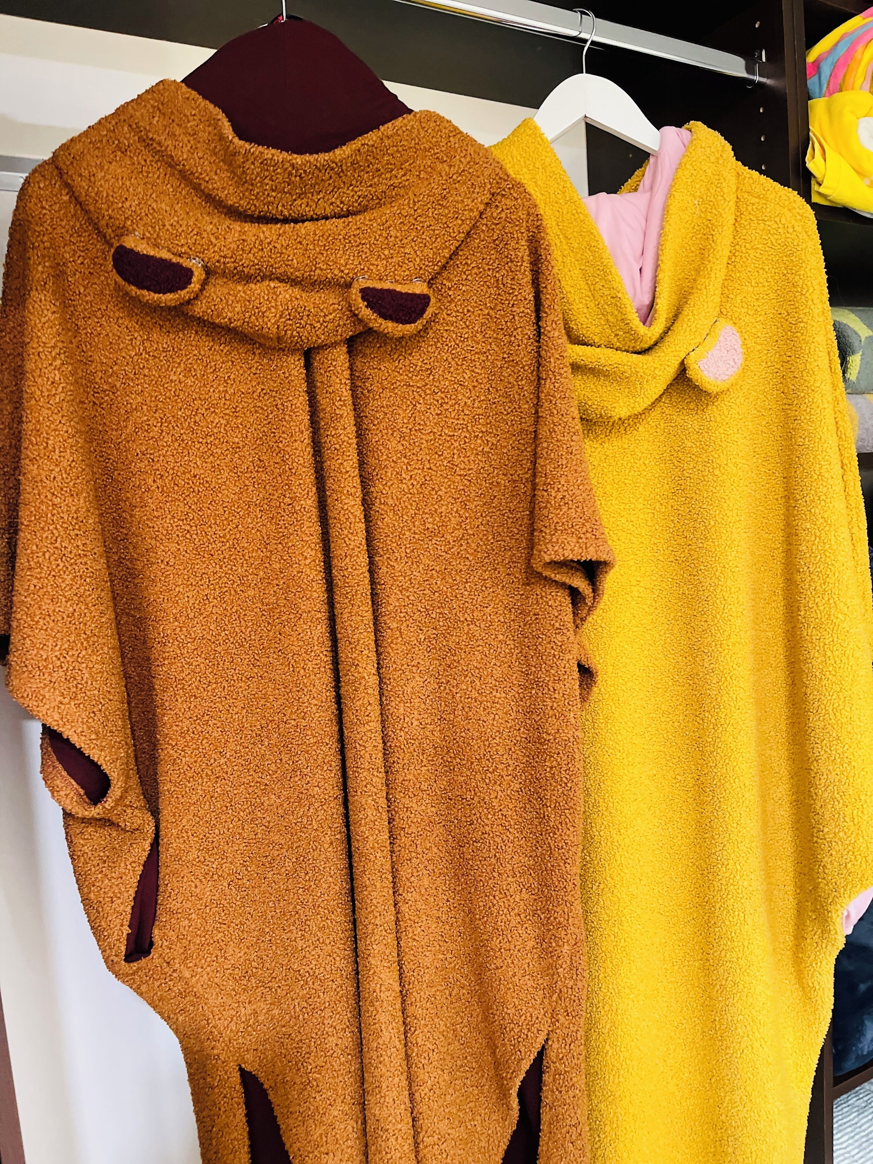 A clothing rack with a mustard-colored coat and a yellow coat.