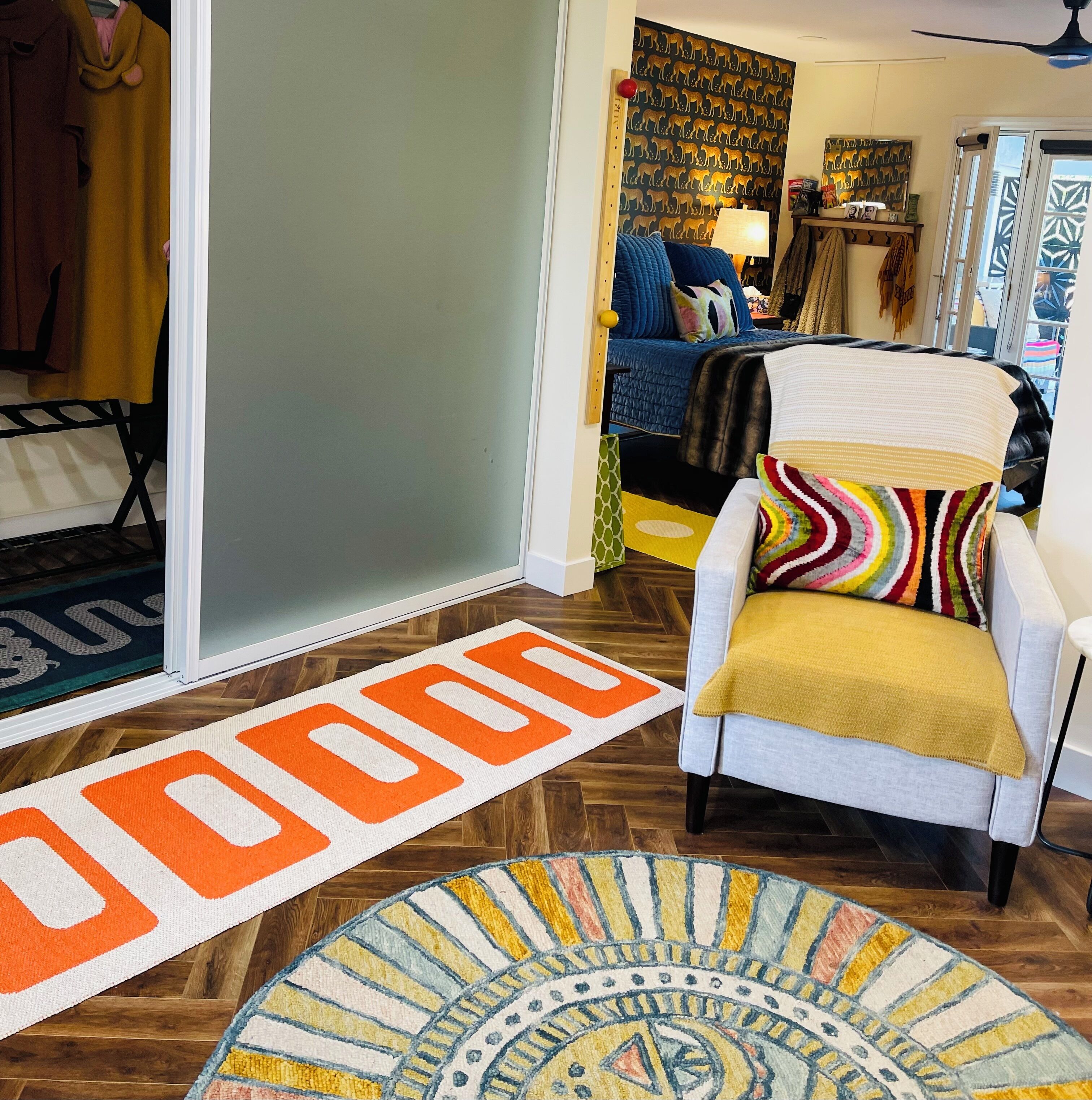 A living room with a blue sofa, a patterned rug, and a door with a 'DOOR' sign.