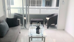 Una sala moderna con una mesa de centro de vidrio, un sofá y dos sillones de mimbre.