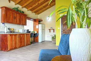 Une cuisine avec des meubles de rangement en bois, un réfrigérateur et un coin repas avec des chaises.