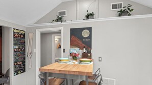 A dining area with a wooden table, metal chairs, and a wall poster. - Music Lover’s Getaway - Red Rocks + Denver (Wheat Ridge)
