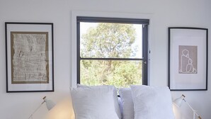 Quarto com cama, duas mesas de cabeceira, uma janela e obras de arte emolduradas nas paredes.